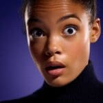 Close-up of a person with wide eyes and mouth slightly open in shock.