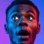 Low-angle shot of a man looking up in awe with blue and red neon lighting.